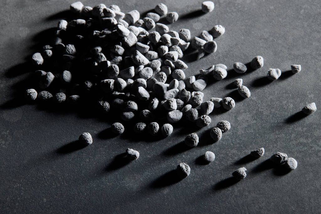 Porous Plenco phenolic resin pellets on a dark textured surface