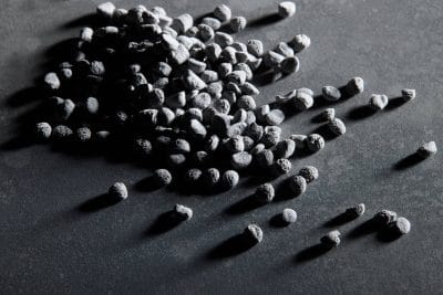 PLENCO phenolic thermoset pellets on a dark textured surface