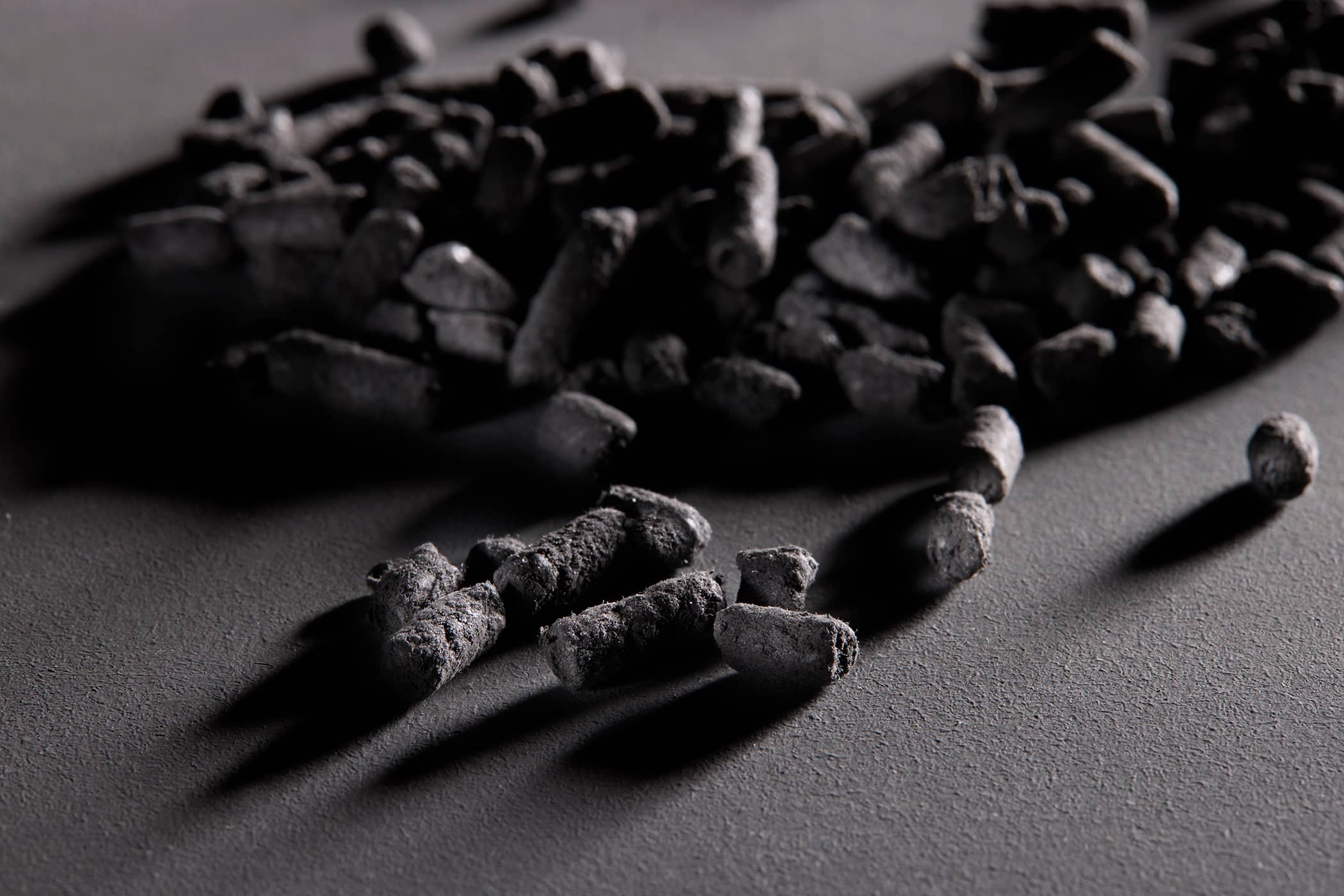 Close-up of black phenolic molding compound pellets for industrial thermoset manufacturing.