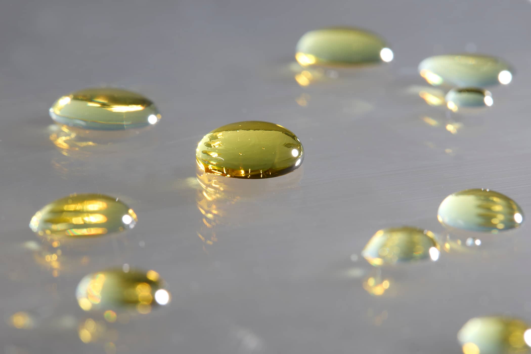 Macro view of golden liquid resin droplets on a metallic surface for technical testing at PLENCO.